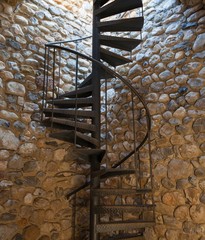 Metal spiral staircase and an old stone wall