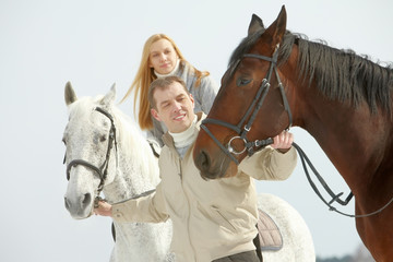 Obraz premium A young man leading two horses, one of them is ridden by a woman