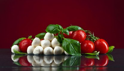 mozzarella with green basil and tomatoes on black table