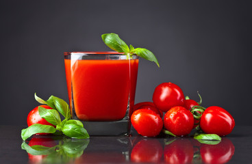 tomato juice with tomatoes and green basil on black table