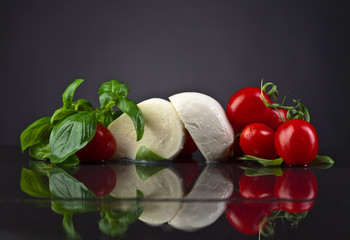 mozzarella with green basil and tomatoes on black table © Igor Normann