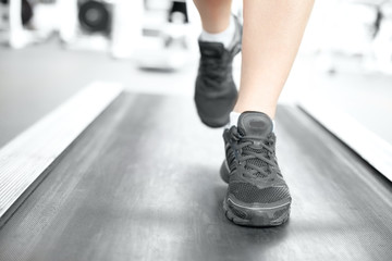 Fototapeta na wymiar Close-up of female legs in sports shoes running on treadmill