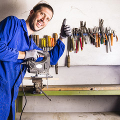 Caucasian handyman using jigsaw with safety gloves and glasses with thumb up