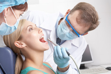 A dentist drilling a young woman s teeth