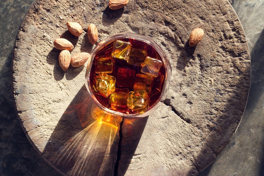 Whiskey bourbon with ices in glass and almonds on old wooden 