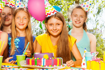 Happy birthday girl in party hat among her friends