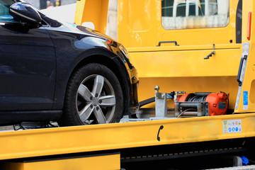 New car transported on yellow tow track.