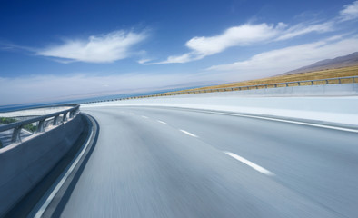 Highway overpass motion blur with mountain lake background .