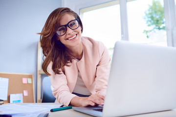 Portrait of happy businesswoman working on laptop