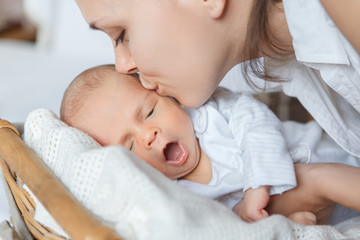 Mother kisses her newborn son before bedtime