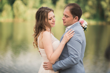 Elegant beautiful wedding couple posing near a lake at sunset