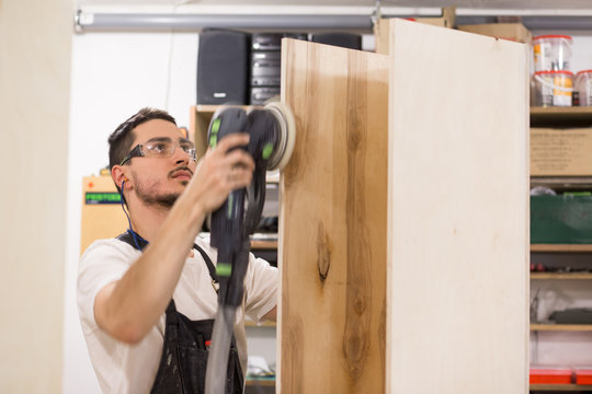 man polishes boards. carpenter with sander