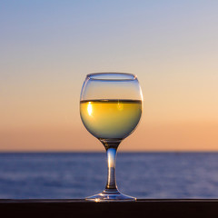 Glass of white wine at sunset on the sea.