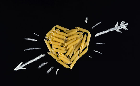 Heart shape made of  penne pasta. Pasta in the shape of a heart on a black background. I love pasta.