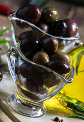 Greek olives in a glass bowl and oils, dark wood background, sel