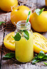 Freshly squeezed juice of yellow tomatoes with basil in a glass