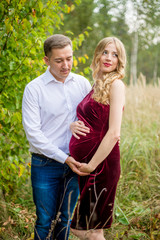 Happy husband hugging his pregnant wife in nature