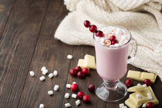 Hot white chocolate with cranberry, knitted blanket and marshmallows on dark wooden background. Winter Christmas time. Selective focus. 