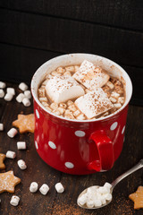 Big red Cup of hot Chocolate drink with Marshmallows and cinnamon on dark wooden background. Winter time. Selective focus