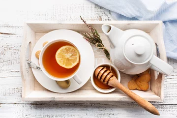 Papier Peint photo Lavable Theé Tray with cup of hot black tea, lemon and honey on white rustic wooden background. Breakfast time. Top view