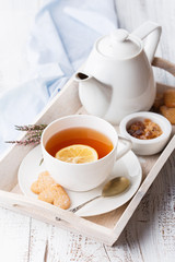 Tray with cup of hot black tea, lemon and honey. Breakfast time