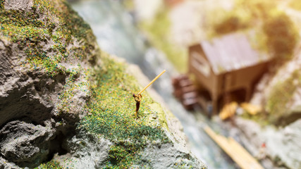 Miniature people: young man playing long trumpet in the mountains. Adventure, travel, tourism, hike and eco nature concept.
