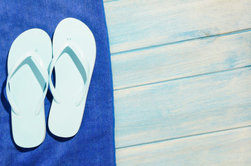 flip flops and towel on blue wooden table with sunlight