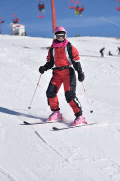 Young woman skiing downhill with blue sky and chairlift in the background
