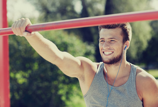 Happy Young Man With Earphones And Horizontal Bar