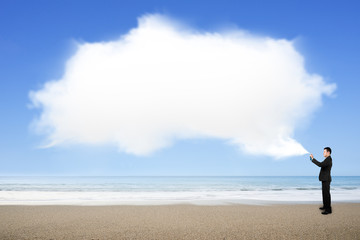 Man spraying white cloud paint on sea beach