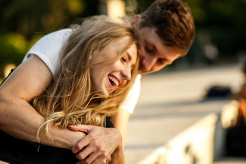 Fototapeta premium Charming lady laughs while she sits in man's embraces