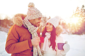 Obraz premium happy couple with tea cups over winter landscape