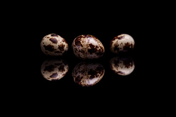 Three quail eggs on black background