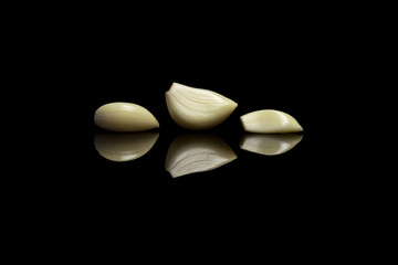 Three peeled garlic on black background