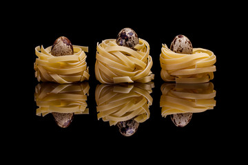 Three nest pasta with quail eggs on black background