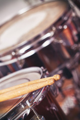 Closeup detail of red drums with focus on drumsticks. Copy space