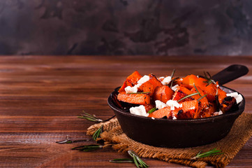Roasted, baked pumpkin with addition aromatic herbs and goat cheese