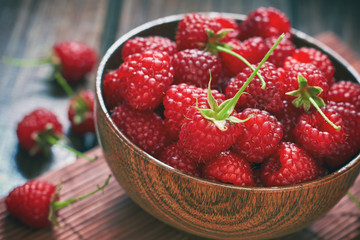 Fresh raspberries in wooden bowl on wooden background