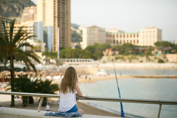 Fototapeta na wymiar Look from behind at young woman watching the city by the sea fro