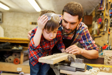 father and little son with wood plank at workshop