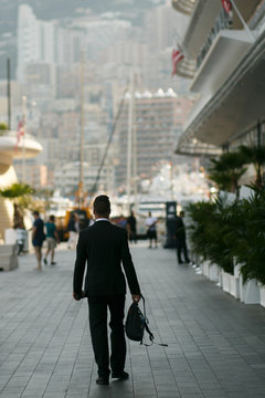 Look From Behind At Tall Man In Black Suit Walking Along The Str