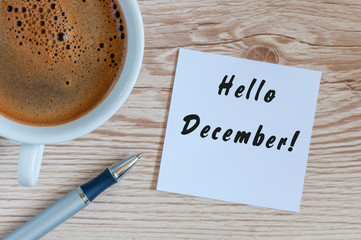 Hello December written on paper near morning coffee cup at manager or freelancer workplace. Eve, Christmas and New year time concept