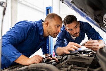 Fototapeta na wymiar mechanic men with wrench repairing car at workshop