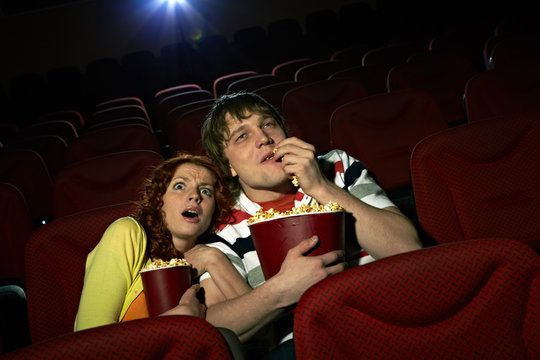 Young girl embracing her boyfriend terrified by the movie