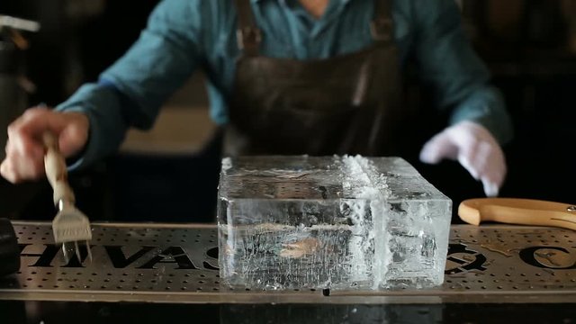 Bartender sawing ice on the bar with a saw