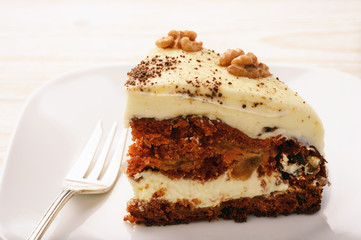 Piece of carrot cake with cheese cream on white background.