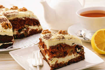 Piece of carrot cake with cheese cream on white background.