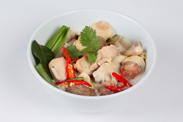Close up focus of chicken and galangal in coconut milk soup and herb on white background. 