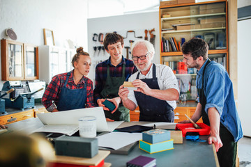 Senior male workshop leader showing materials to young group of men and women in book arts workshop