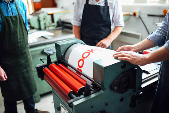 Craftspeople being shown how to use letterpress machine in book arts workshop, mid section